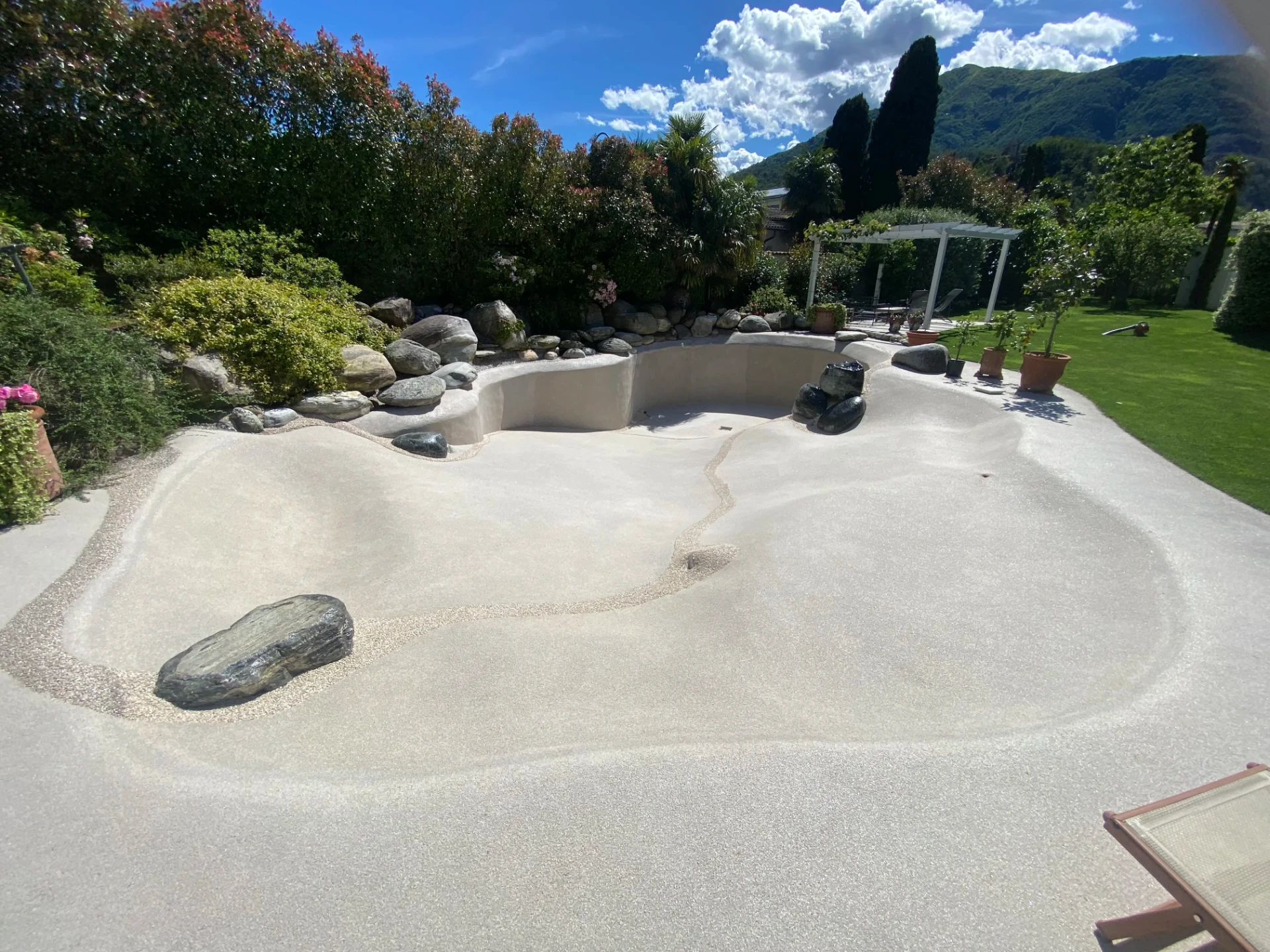Naturi sand-bottom pool shell with hand-sculpted vertical walls and natural stone edging